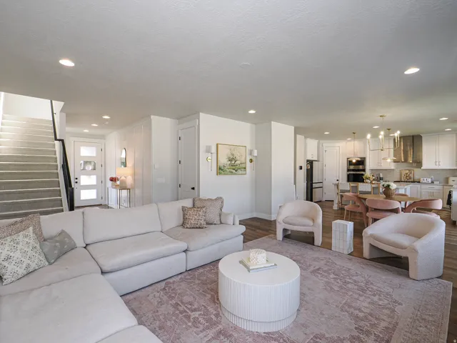 Open-concept living space featuring wood-finish flooring, recessed lighting, and a modern staircase with a dark railing