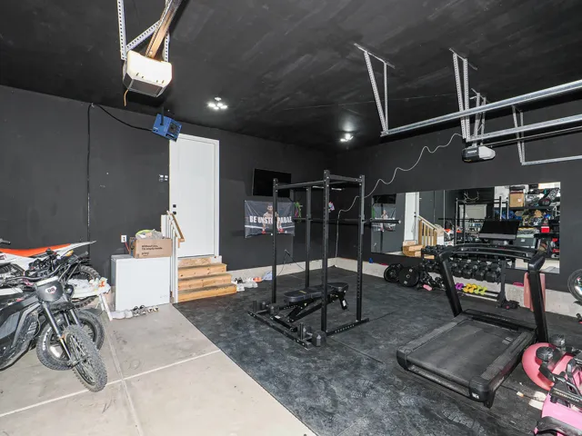 Garage space featuring concrete flooring, a side entry door with wood stairs, and mounted mirrors