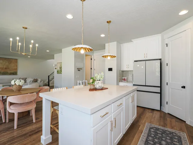 Expansive kitchen island with a light-toned countertop, white cabinetry with gold-toned hardware, and recessed lighting