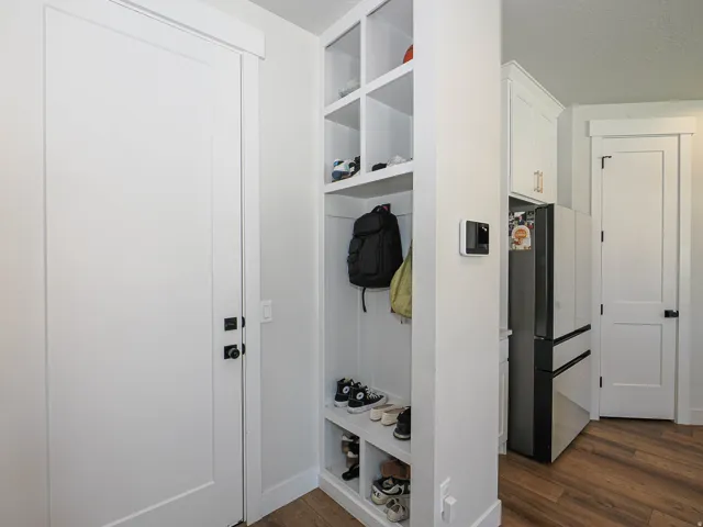 Built-in storage solutions, white flat-panel doors, dark hardware, wood-finish flooring, and white cabinetry
