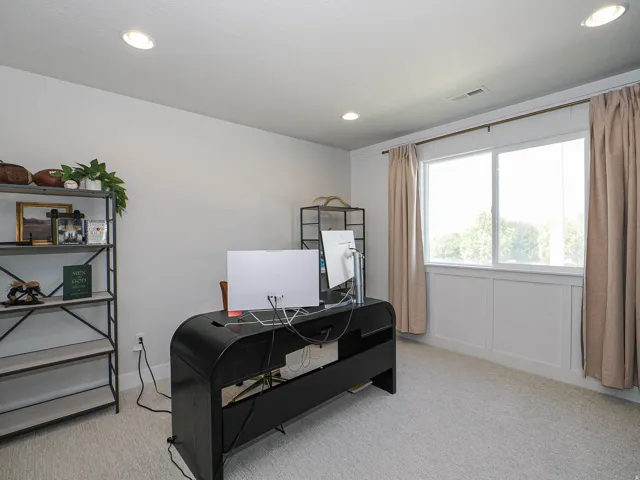 Recessed ceiling lighting, light-toned carpeting, crown molding, and wainscoting detail under a dual-pane window