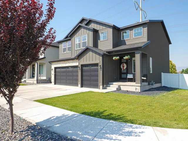 Contemporary exterior with vertical and horizontal siding, stone accent details, a covered front porch, and a two-car garage