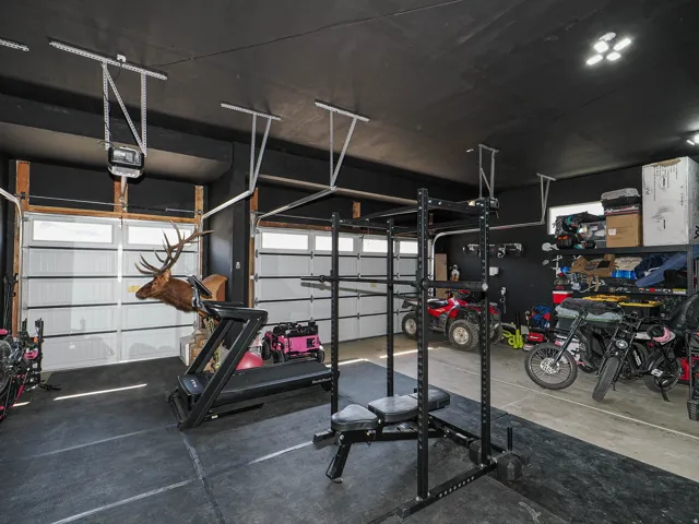 Garage space featuring a painted black ceiling, multiple overhead lights, and two garage doors with upper window panels