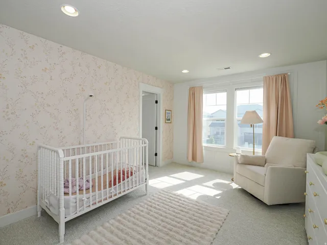Recessed ceiling lighting, patterned wall covering, white trim, light-toned carpet, and a white interior door