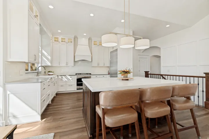 Kitchen featuring white shaker cabinetry, stainless steel appliances, a center island with countertop seating, and wood-finish flooring