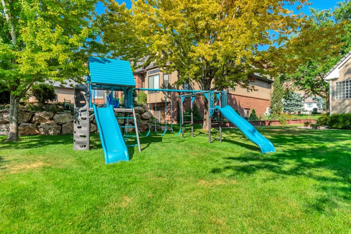 Expansive lawn area featuring mature trees and a rock retaining wall