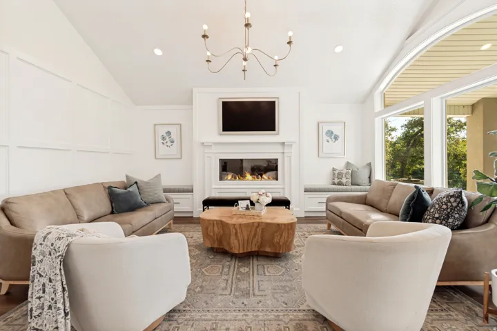 Sophisticated living room showcasing a dual-fireplace design with built-in cabinetry, a gas fireplace with a linear insert, and a wall-mounted flat-screen television