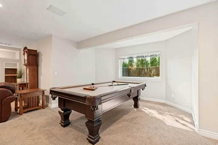 Recessed ceiling lighting, broad wall-to-wall carpeting, and a window with outdoor landscaping