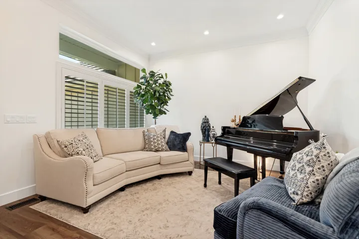 White walls with crown molding, wood-finish flooring, recessed lighting, and a large window with plantation shutters