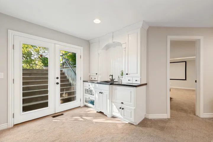Wet bar featuring white cabinetry, dark countertop, and integrated sink