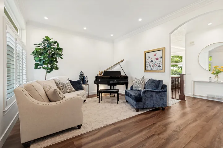 Recessed lighting, crown molding, wood-finish flooring, white plantation shutters, and an arched entryway