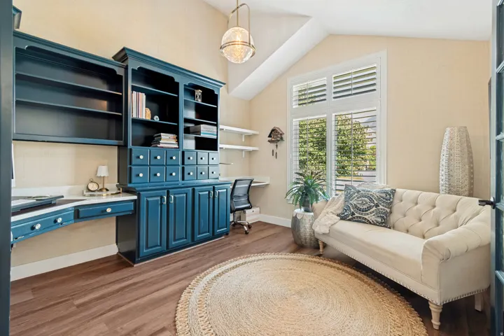 Wood-finish flooring, built-in cabinetry with desk space, vaulted ceiling, and window with plantation shutters