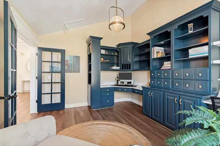 Built-in custom cabinetry with a corner desk, wood-finish flooring, and a vaulted ceiling with an attached light fixture
