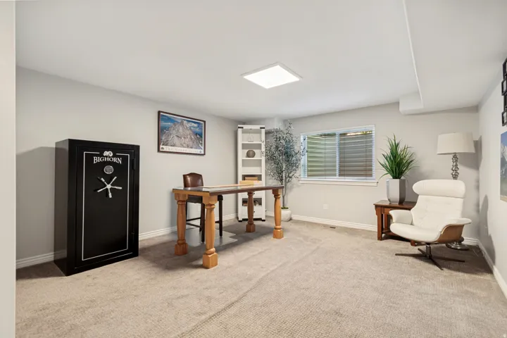 Spacious office features neutral carpeting, abundant natural light from large windows with plantation shutters, recessed ceiling lighting, and built-in shelving