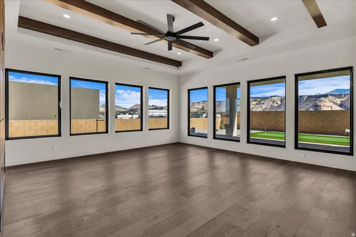 Tray ceiling with dark wood beams, recessed lighting, and a ceiling fan