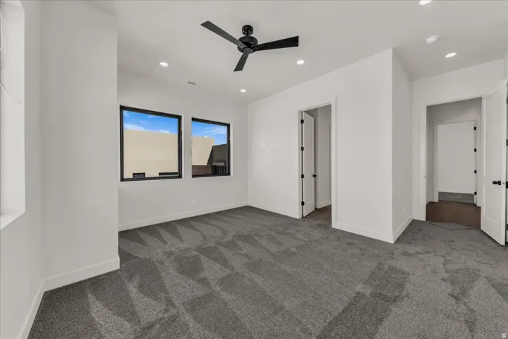 Bright room with multiple windows, recessed lighting, and a ceiling fan with black blades