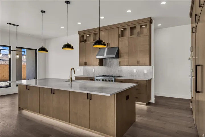 Gourmet kitchen with a large central island, light wood-finish cabinetry, stainless steel appliances, and integrated lighting