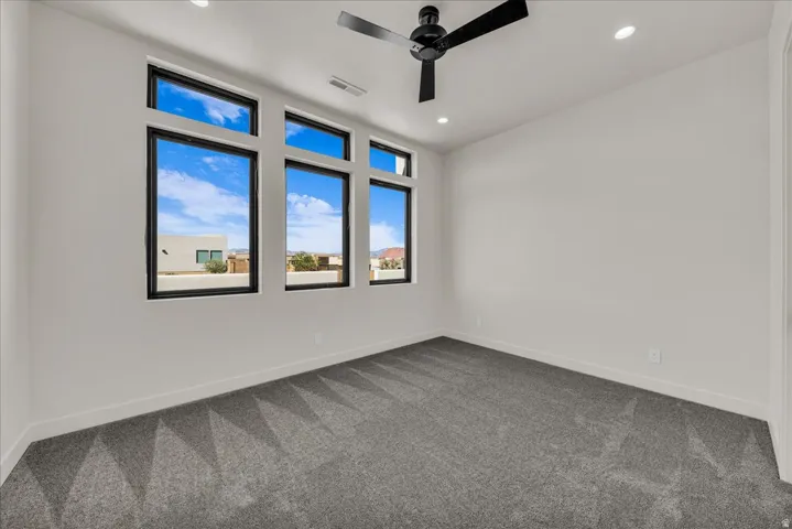 Room featuring multiple windows with black frames, a ceiling fan, recessed lighting, and grey carpet