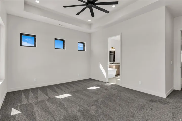 Recessed lighting, tray ceiling, ceiling fan, and carpeted flooring