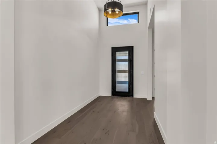 Hardwood-finish flooring, high ceilings, contemporary chandelier, transom window, and a modern entry door with glass panels