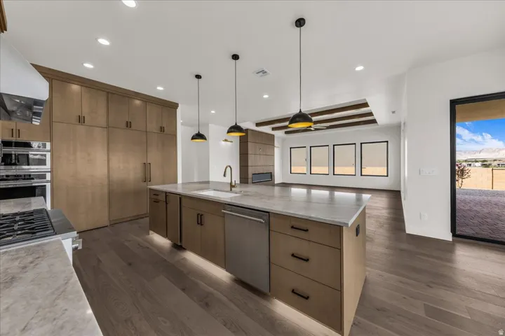 Gourmet kitchen with extensive cabinetry, a large center island with integrated sink, stainless steel appliances, and wood-finish flooring