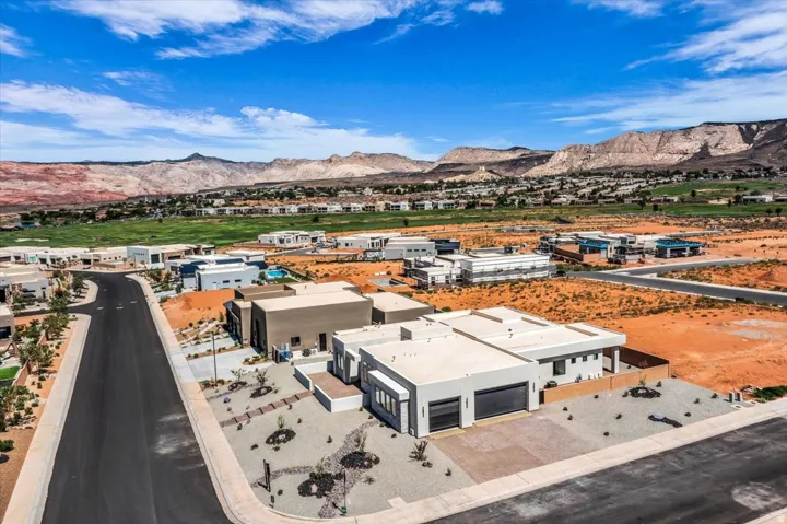 Modern desert community with a paved street, extensive landscaping, and distant mountain scenery