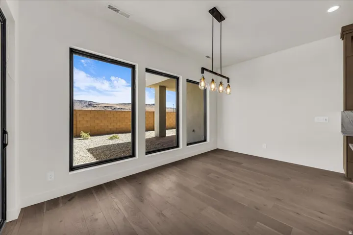 Hardwood-finish flooring, contemporary chandelier, high ceilings, expansive windows with black frames, and white walls