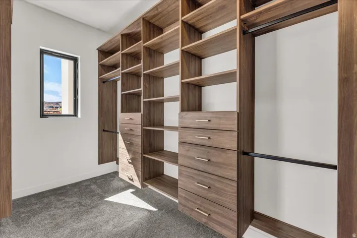 Custom walk-in closet featuring extensive wood-finish cabinetry with multiple shelving sections, four built-in drawers with metal hardware, and dual clothing rods