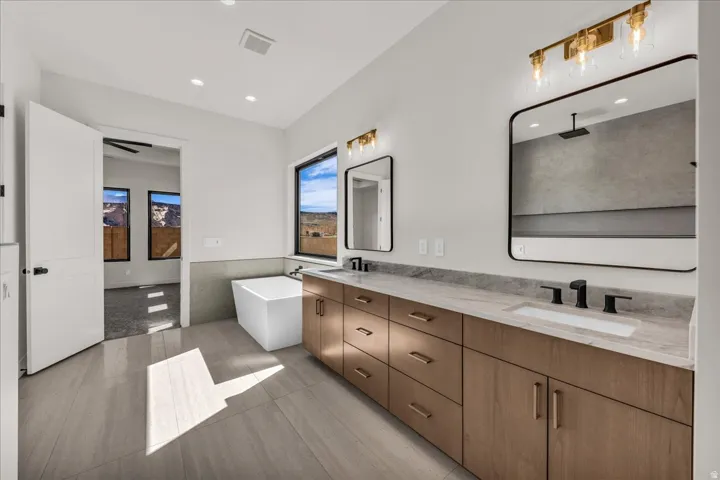 Dual vanity with undermount sinks, wood-finish cabinetry, and matte black fixtures