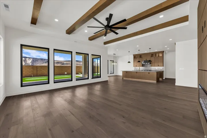 Wide plank wood-finish flooring, exposed wood beams, recessed lighting, and a linear electric fireplace