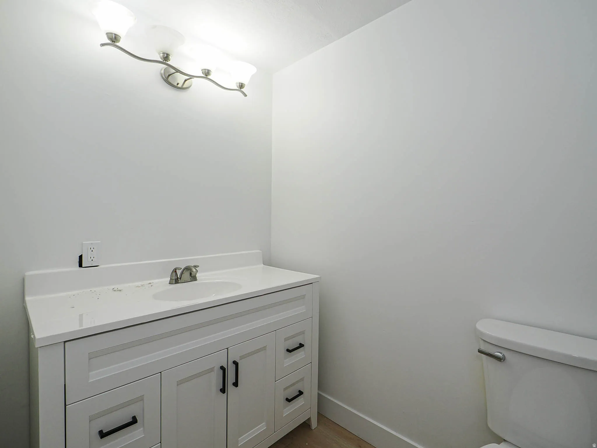 Bright, freshly appointed bathroom featuring a white vanity with dual drawers and black hardware, white quartz countertop, chrome faucet and fixtures, and recessed ceiling lighting