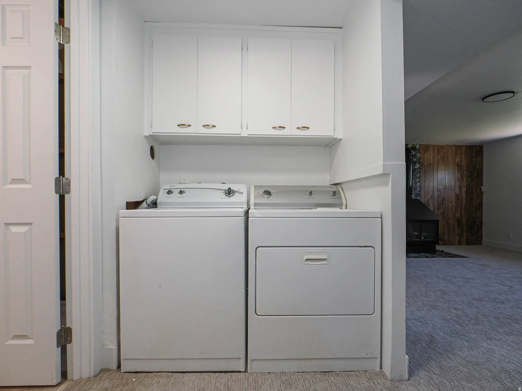 Laundry area featuring white cabinetry with gold-tone hardware, a white washer, and a white dryer