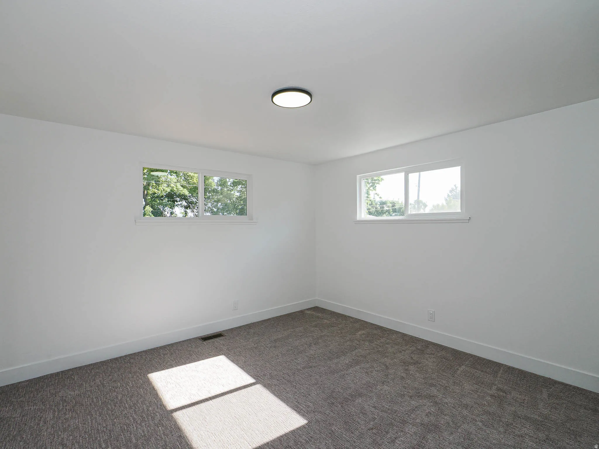Recessed lighting, neutral paint, and gray carpet flooring
