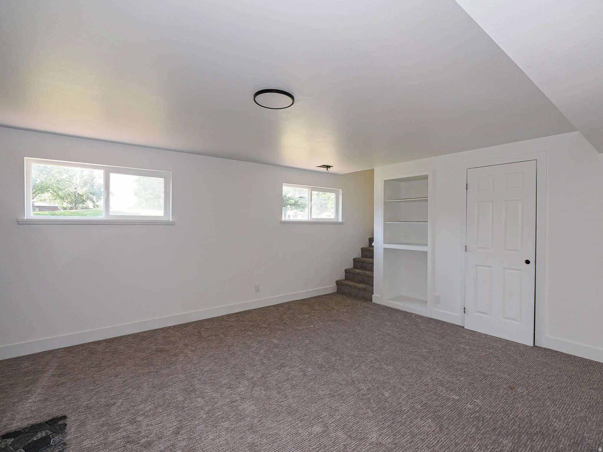 Plush carpeting, recessed lighting, and a built-in shelving unit
