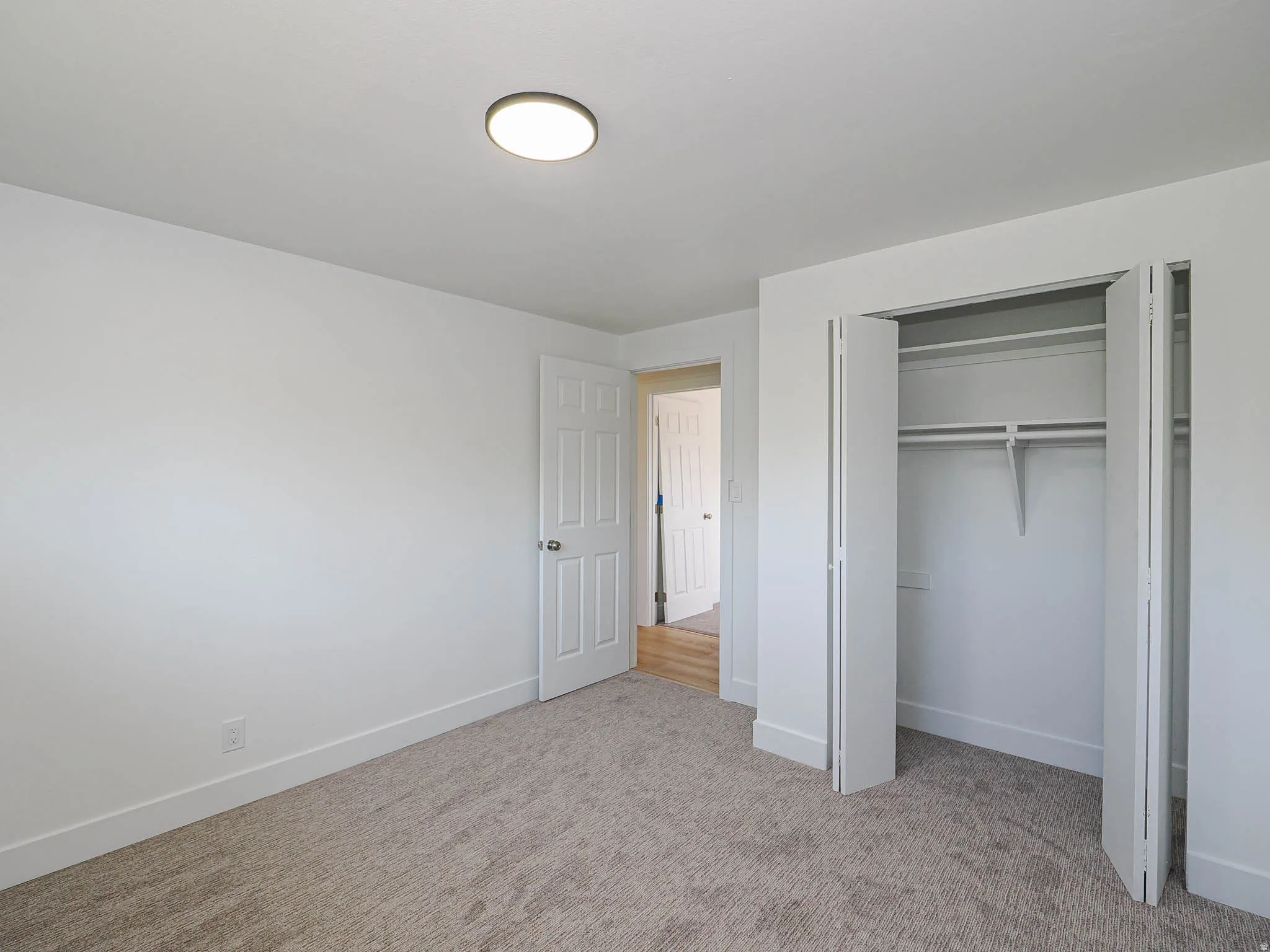 Neutral-toned carpet flooring, white walls, and a flush-mount ceiling light