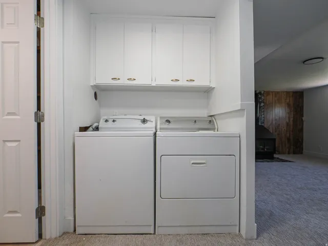 Laundry area featuring white cabinetry with gold-tone hardware, a white washer, and a white dryer