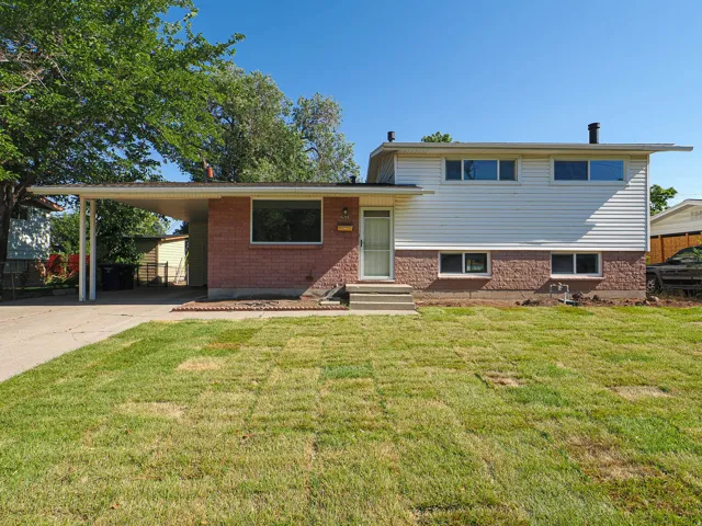 Brick and siding exterior with a covered carport, concrete driveway, and front entryway with steps