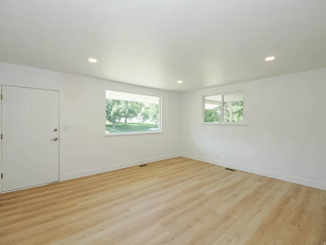 Recessed lighting illuminates the open area with light wood-finish flooring