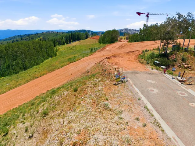 Roadside property featuring a paved entry, natural landscaping, and distant mountain ranges