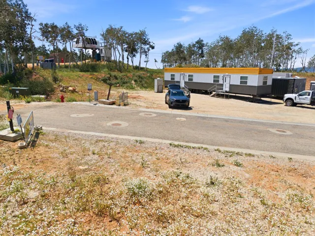 Gravel lot featuring a portable building with a yellow fascia and gray siding, multiple entryways, and a gravel parking area