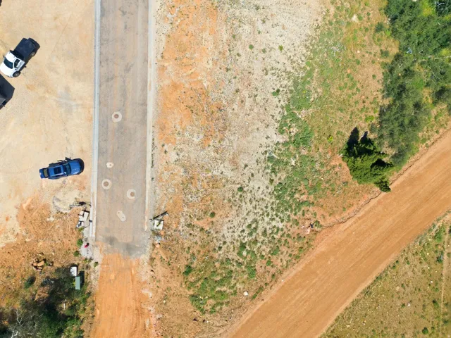 Expansive land parcel featuring a paved road, a dirt road, and visible utility access points