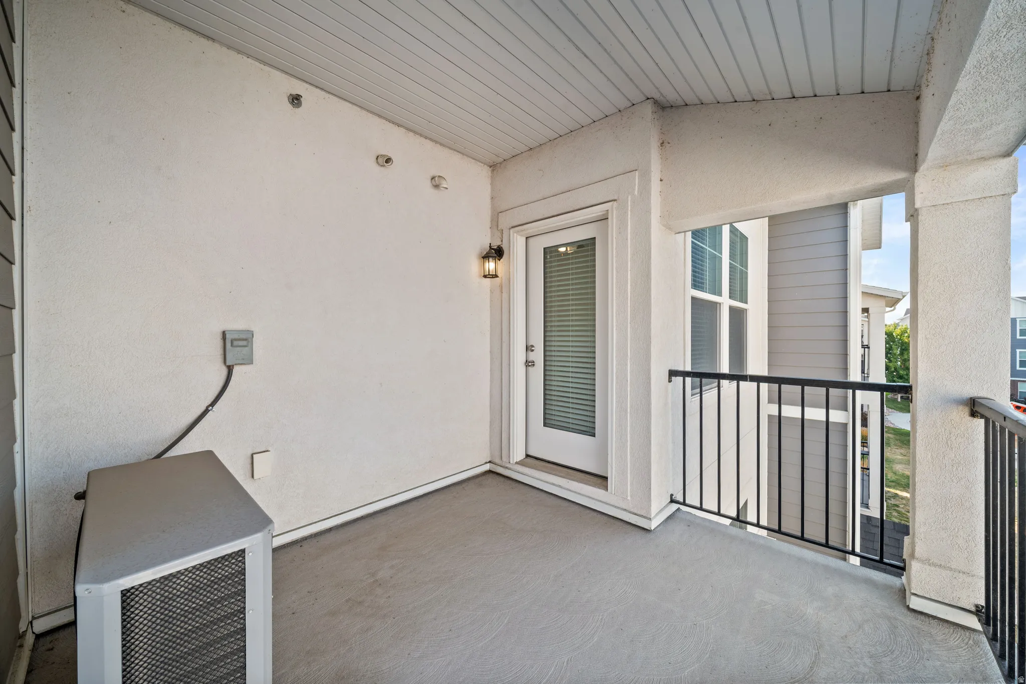 Spacious covered porch with composite decking, metal railings, and glass French doors providing access to the interior
