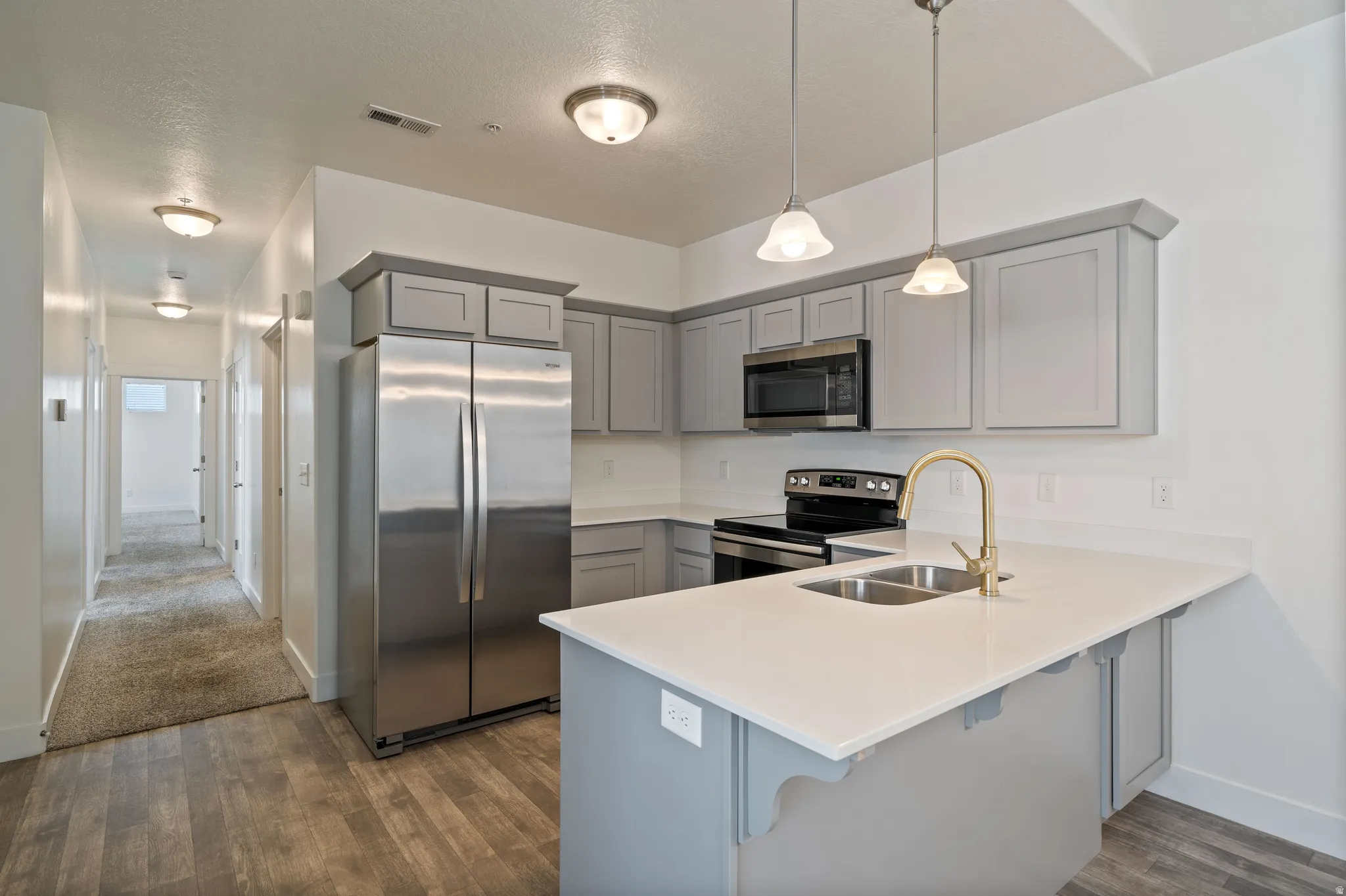 Kitchen featuring a stainless steel refrigerator, microwave, and range