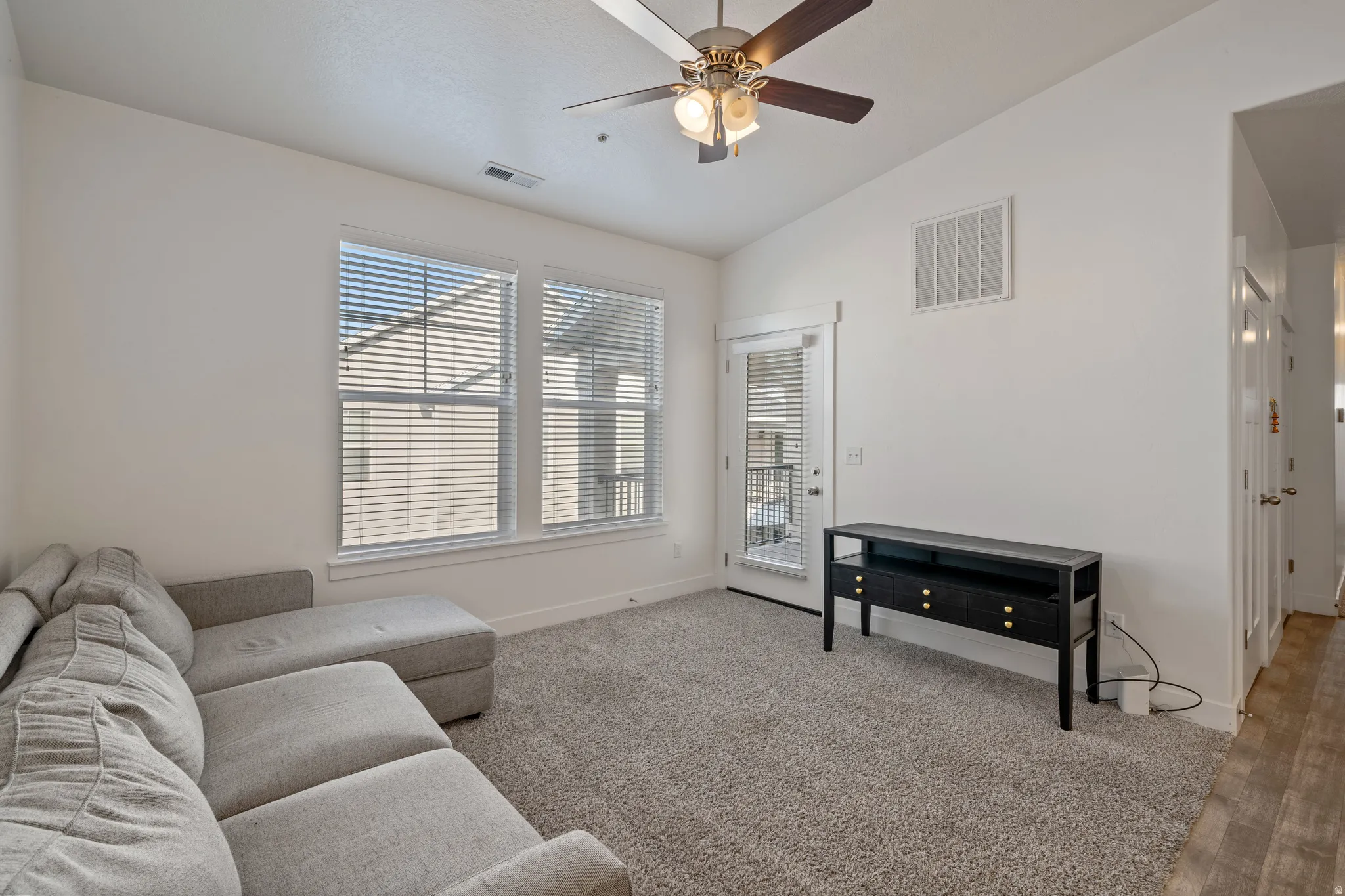 Bright and spacious living area bathed in natural light through dual large windows with plantation shutters