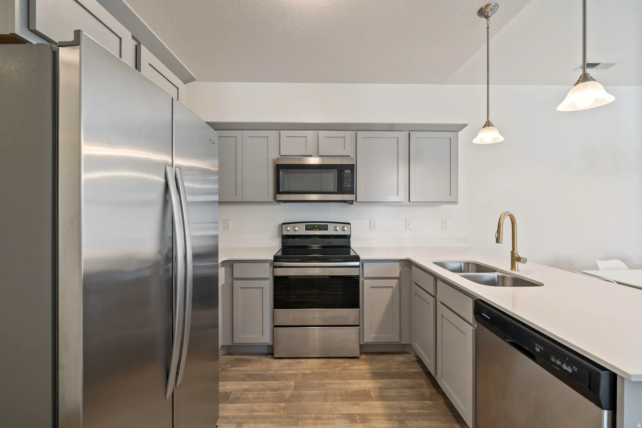 Modern kitchen featuring stainless steel appliances, including a French-door refrigerator, electric range with microwave, and dishwasher