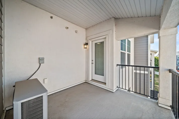 Spacious covered porch with composite decking, metal railings, and glass French doors providing access to the interior