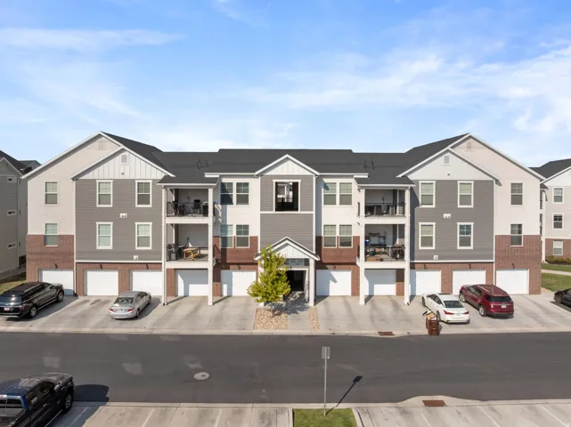Modern townhome community featuring distinctive two-tone exterior with taupe and brick detailing, pitched rooflines with multiple gables, and ground-level garage parking