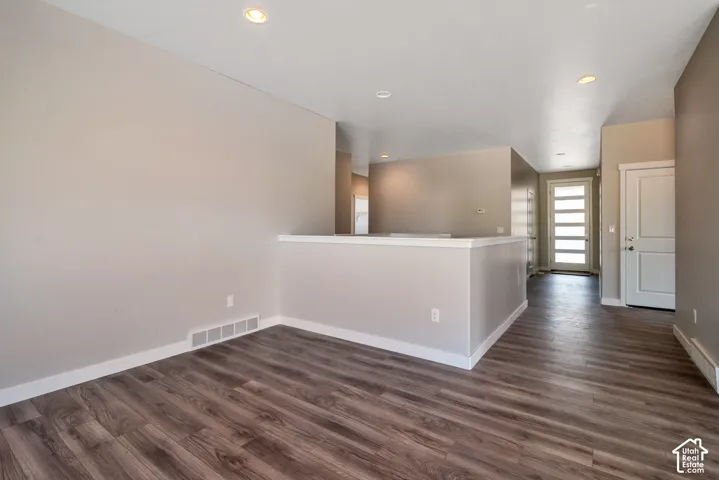 Wood-finish flooring, recessed lighting, neutral wall tones, white trim, and a modern entry door with frosted glass panels