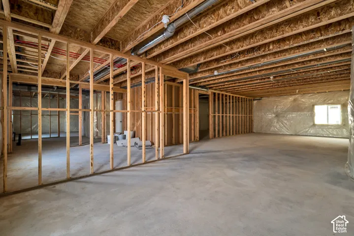 Unfinished basement with concrete flooring, visible framing, and exposed ceiling joists