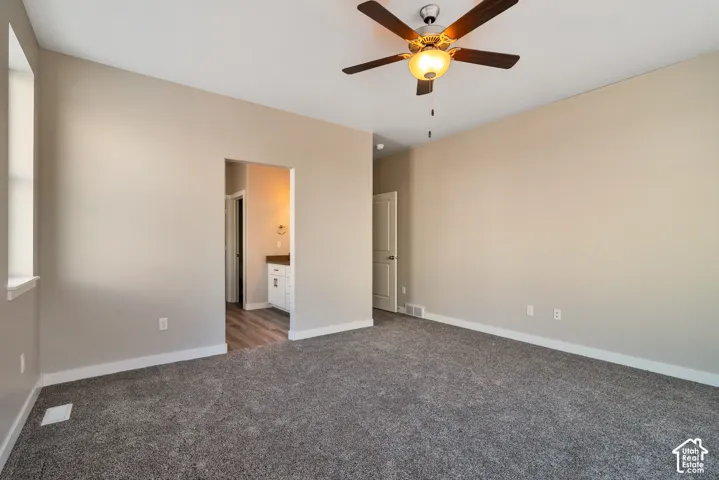 Recessed window, ceiling fan with integrated lighting, neutral wall palette, textured carpeting, and a doorway leading to an additional space with wood-finish flooring